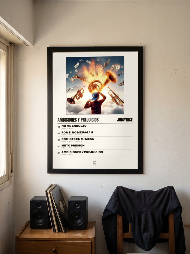 Póster de Ambiciones y Prejuicios de JuicyNise enmarcado en una pared, en un ambiente real