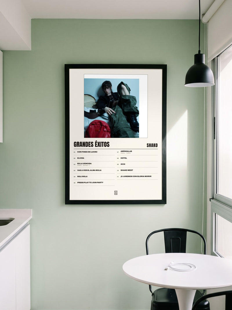 Póster de grandes éxitos de Shako enmarcado en una pared, en un ambiente real