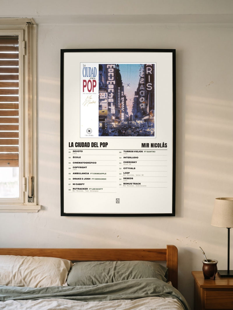 Póster de La Ciudad del Pop de Mir Nicolás enmarcado en una pared, en un ambiente distinto