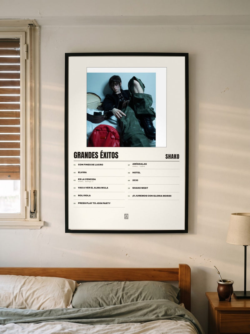 Póster de grandes éxitos de Shako enmarcado en una pared, en un ambiente distinto